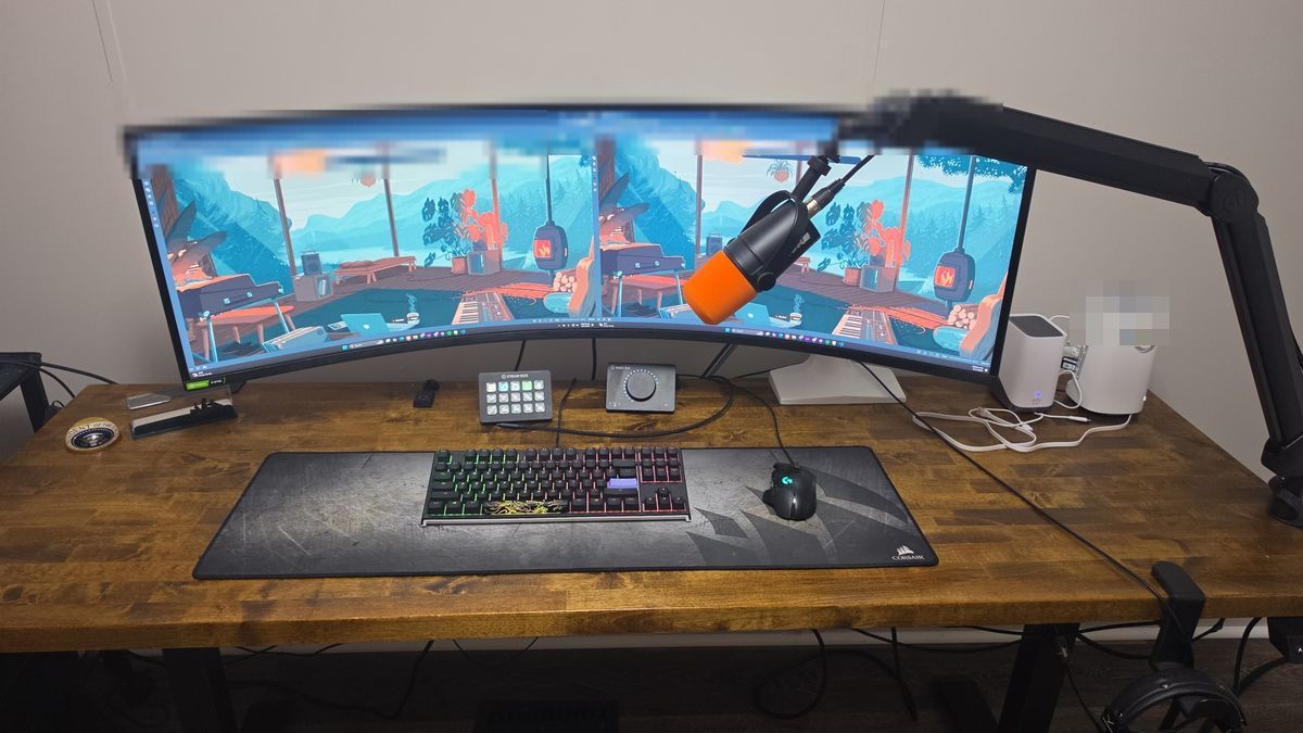 My standing desk from above: a stained butcher block top on a FEZIBO frame, with the 49 inch curved monitor, keyboard, Stream Deck, audio interface and the mic on its arm